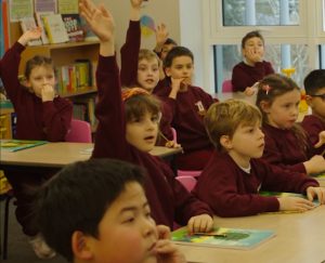 A picture of a primary school class who have raised their hand to answer a question